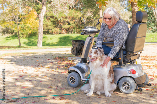 An elderly woman in a mobility scooter with her dog in an Autumn setting photo
