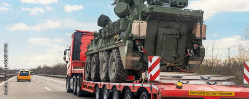 Back view armoured personnel carrier stryker with air defense system trailer hauler carrier truck drive military convoy highway road. US troops moving reloceation force reinforcement eastern Europe photo