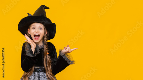 A surprised girl in a witch's fancy dress points to the side at the advertisement and the ad, the place for advertising in the photo with an attractive witch, a funny witch points to the sign.