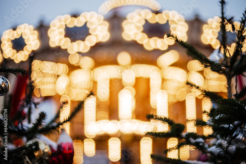 Out of focus is a blurry large carousel with lights. Beautiful Christmas background with space for text and greetings