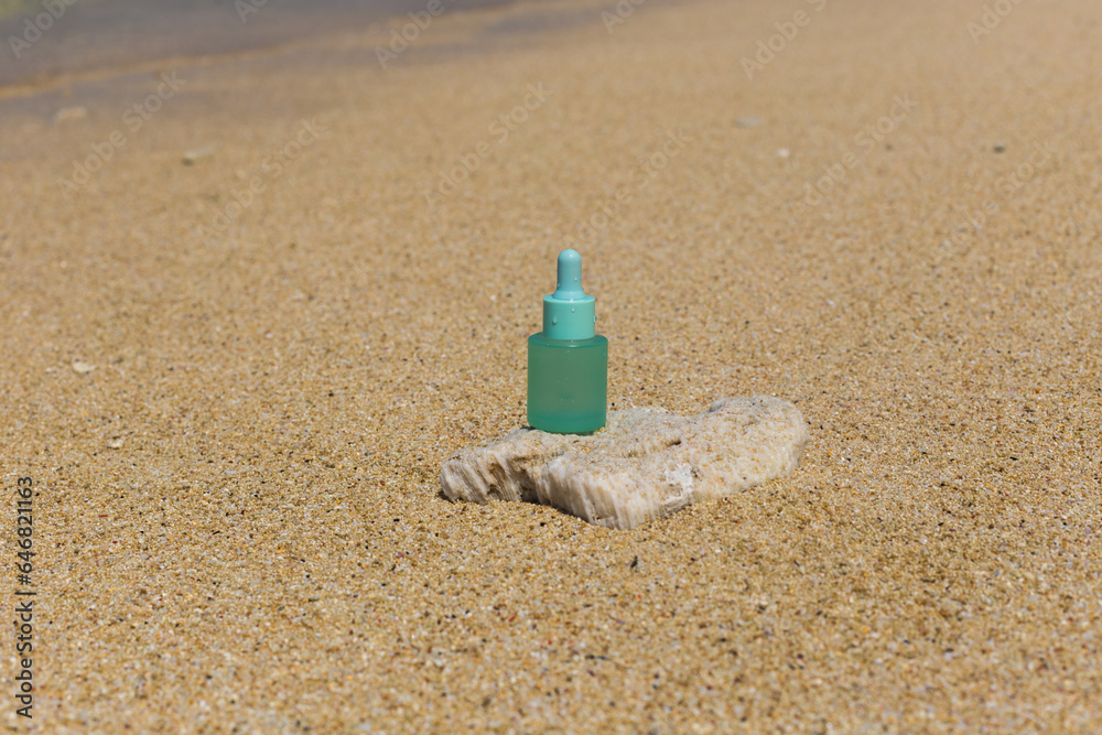 Glass bottle of face serum with pipette on a stone on a sandy beach. Stylish concept of care cosmetics and acne prevention. Moisturizing and cleansing the skin Glass bottle of face serum with pipette on a stone on a sandy beach. Stylish concept of care cosmetics and acne prevention. Moisturizing and cleansing the skin