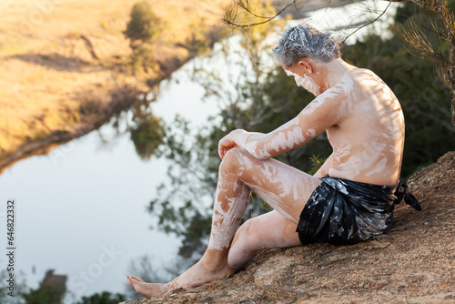 Light skinned aboriginal young man sitting on cliff edge in Wonnarua country photo