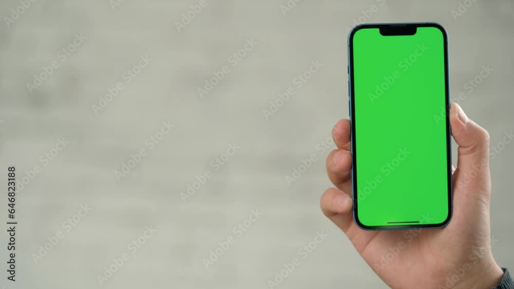 Close up of Phone With Green Screen Mock-Up In Men's Hands Against Background of White Wall Close up of Phone With Green Screen Mock-Up In Men's Hands Against Background of White Wall