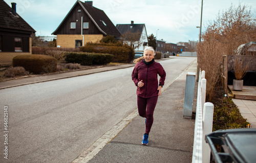 Senior caucasian woman jogging and exercising in the suburbs photo