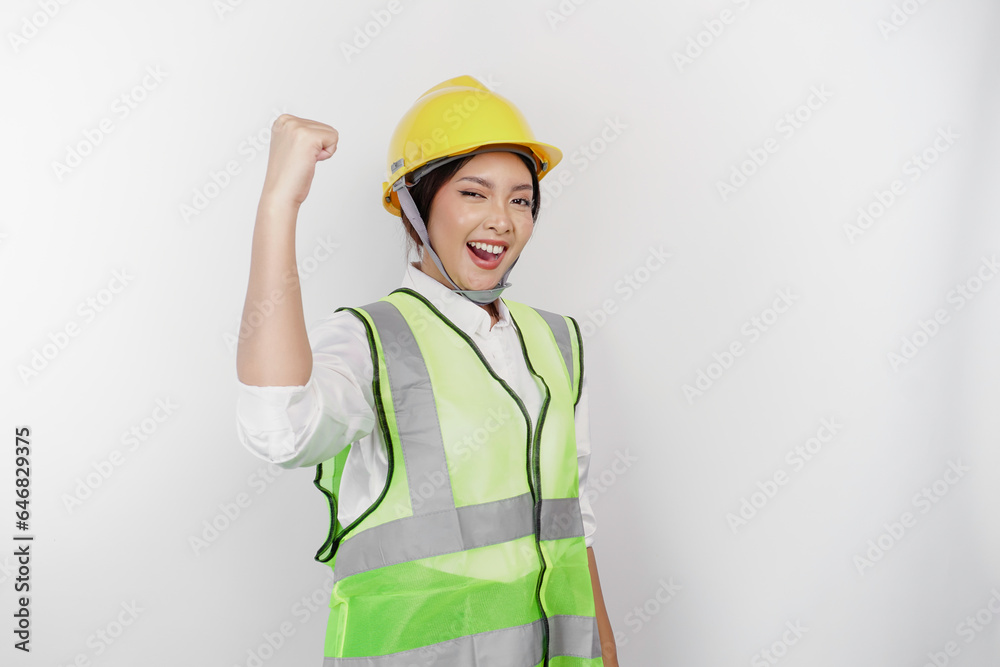 A successful young woman labor is wearing safety helmet and vest, isolated by white background. Labor's day concept.