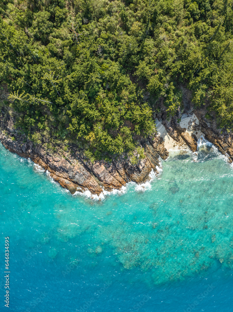 Fototapeta premium High angle aerial bird's eye drone view of the rocky coastline and tiny beaches on Arkhurst Island, a small islet near Hayman Island, Whitsunday Islands, Great Barrier Reef, Queensland, Australia.