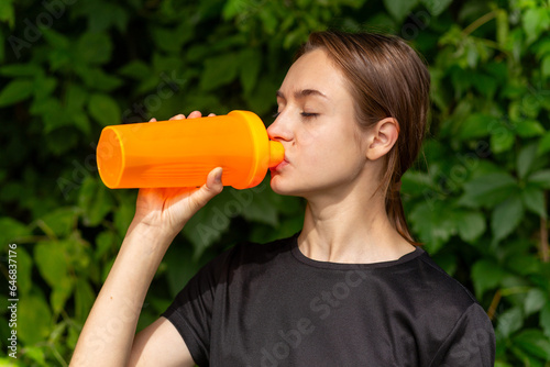 Fit tennage girl runner outdoors holding water bottle. photo