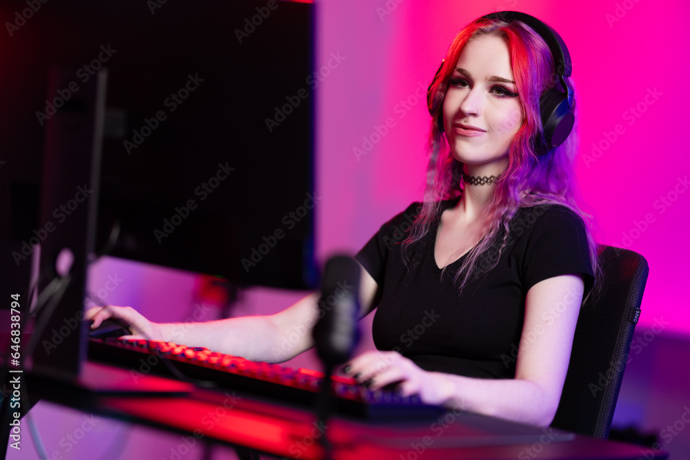Fototapeta premium Focused professional e-sport gamer girl streaming and plays online video game on PC