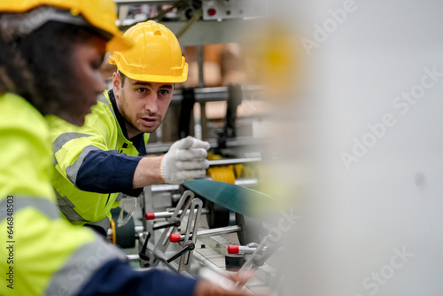 Industrial worker indoors in factory. Young technician with orange hard hat. Smart Caucasian factory worker wearing hardhat and working in power plant.