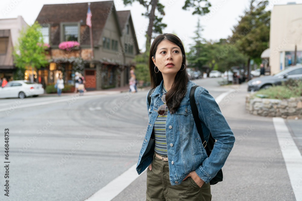 curious asian Taiwanese female visitor looking at her surrounding near the hotel during her stay in the beach town Carmel by the sea California usa
