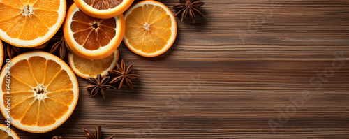 Orange slices with spices are served on a wooden background. Rustic banner with copy space for text.