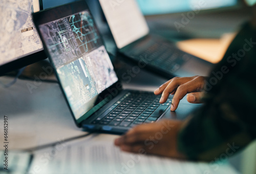 Hands typing, laptop and closeup on table of military intelligence, map and research on internet. Computer, soldier and veteran online for surveillance, cyber security and info of army professional photo