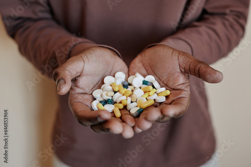 Close up of unrecognizable black man holding handful of pills to camera, copy space