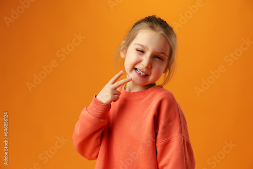 Teen girl happy positive makes peacel v-sign on yellow background photo