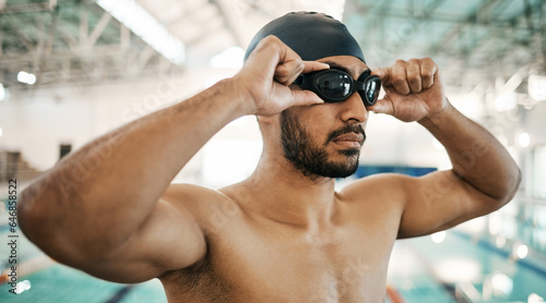 Getting ready, man and goggles for swimming training, competition or a race in the pool. Fitness, gym and an athlete or swimmer with glasses to start exercise, workout or cardio in a triathlon photo