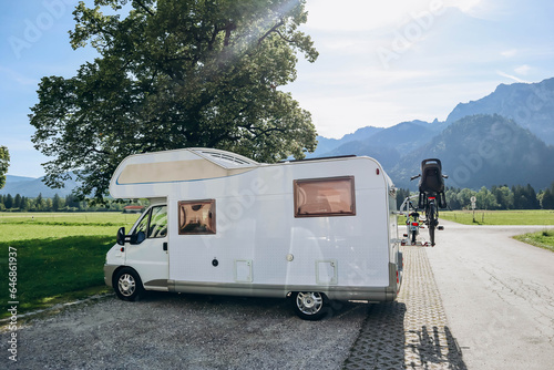 White trailer for road trips, with bicycles behind, in the green meadows of Bavaria, Germany