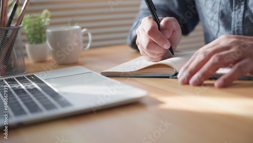 фотографія Close-up of man hand using writing pen memo on notebook paper or letter, diary on table desk office