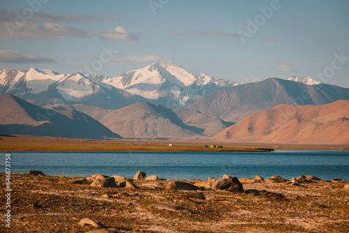 Incredibly beautiful lake Karakul or Karakol. Colorful colors of snowy mountains and sandy hills. Incredible berquoise water of the lake.