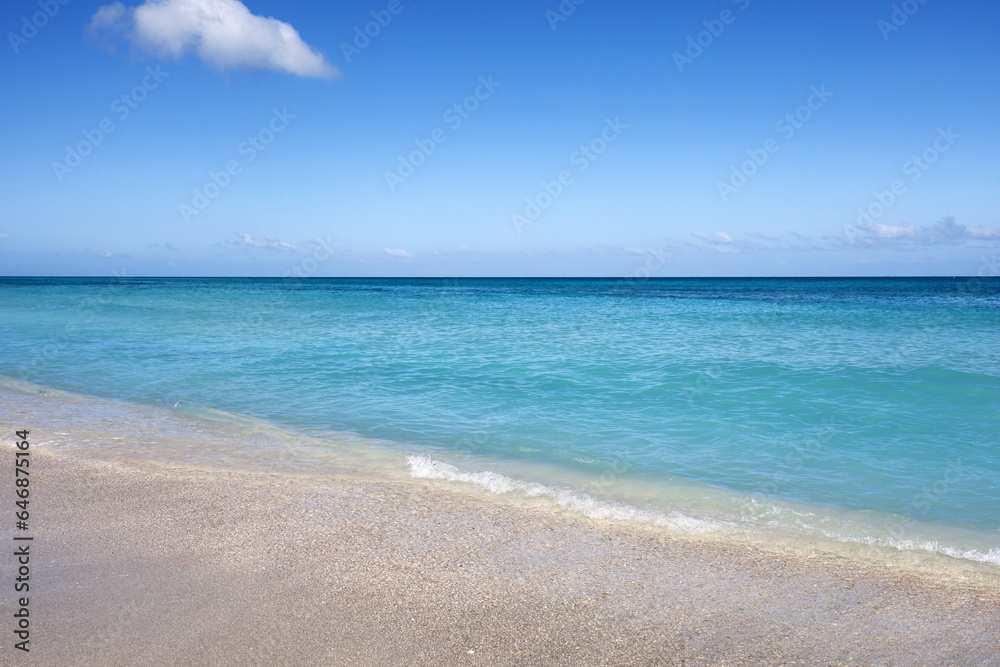 Empty sea beach with white sand, view to azure waves and blue sky with cloud. Caribbean coast, background for holidays on a paradise nature