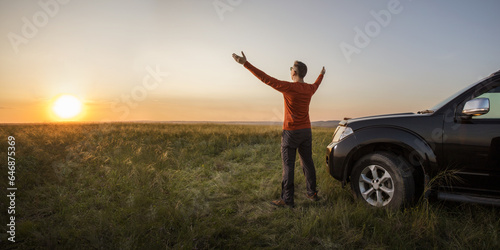 man traveling exploring, enjoying the view of the nature at sunrise. man standing near his car on vacation and watching the sunset at nature.