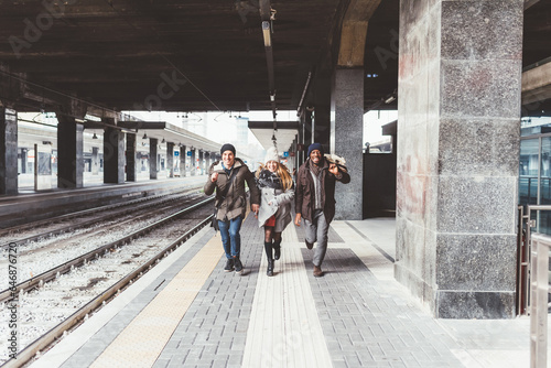 three young multiethnic friends running railway station