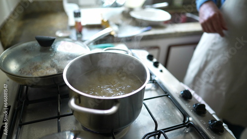 Close-up of boiling water inside metal pan in kitchen stove, preparing food routine
