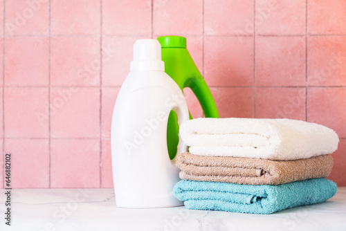 Clean towels and washing gel detergent in the laundry or bathroom against tile wall.