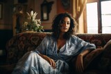 a photo of a gorgeous young african woman sitting on a couch in a living room with morocco-inspired style interior, much color contrast, orange and cyan blue
