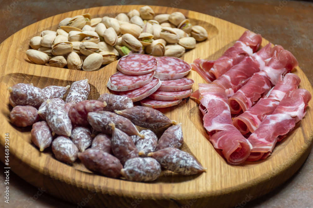 Wooden tray with sausages, pistachios and prosciutto Wooden tray with sausages, pistachios and prosciutto