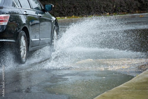 a car driving through the puddle and splashing water in a raining day