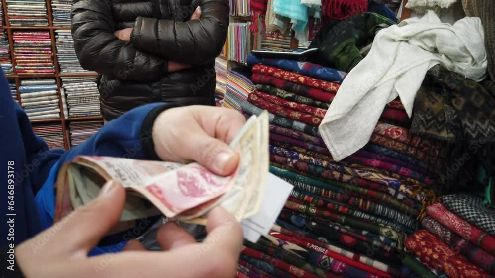 Close-up shot of a tourist counting rupee money in a vibrant cashmere fabric market in Kathmandu, Nepal. Close-up shot of a tourist counting rupee money in a vibrant cashmere fabric market in Kathmandu, Nepal.