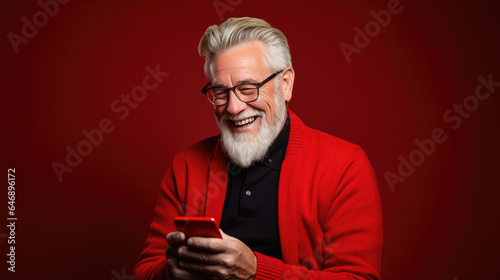 An elderly man smiling and laughing with his phone against a colored background. © MP Studio