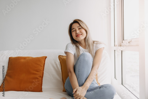 Happy asian women sitting on sofa look at camera at apartment.