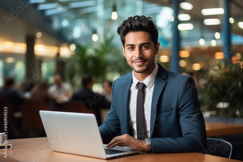 Young businessman or corporate employee using laptop at office