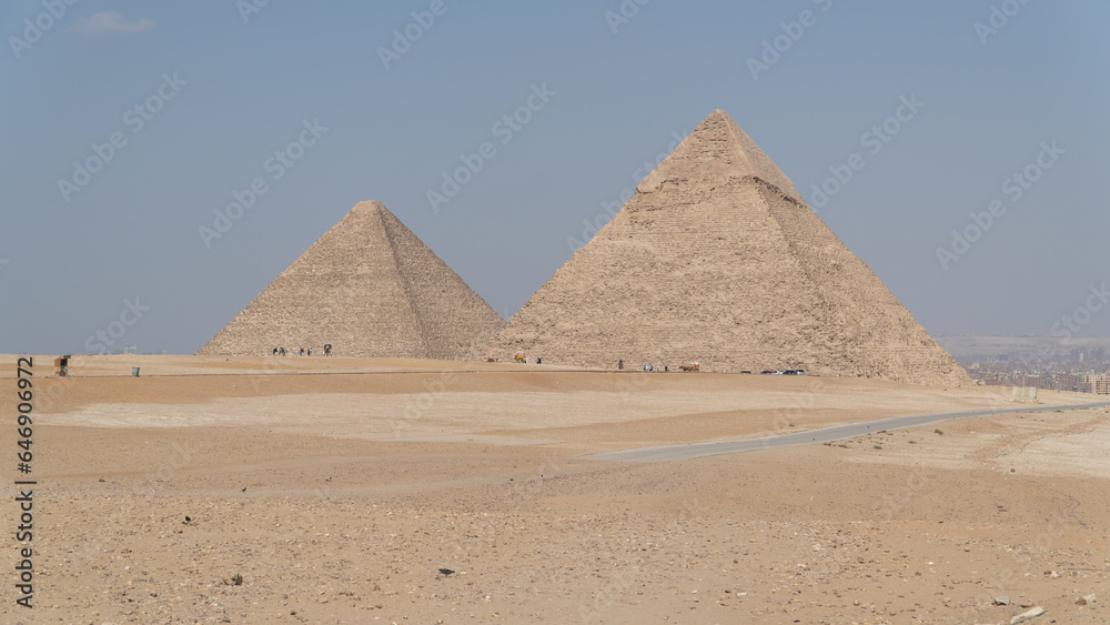 Aerial and frontal view of the Pyramids of Giza, including Cheops, Chephren and Mykerinos in the middle of the desert. In the background is seen the city of cairo or giza of egypt. Aerial and frontal view of the Pyramids of Giza, including Cheops, Chephren and Mykerinos in the middle of the desert. In the background is seen the city of cairo or giza of egypt.