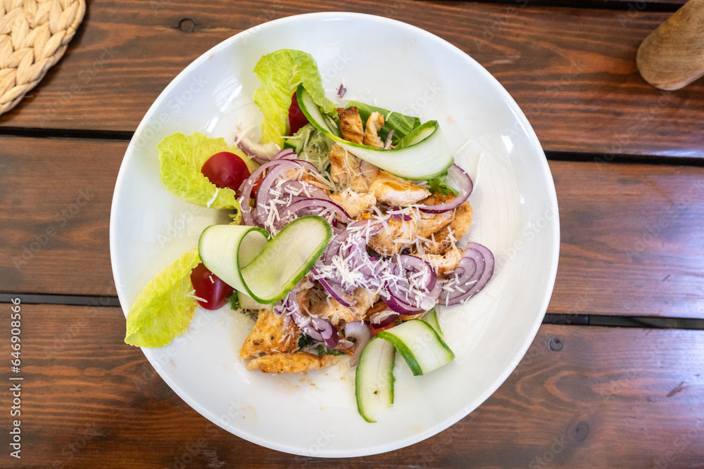 Caesar Salad Closeup, Grilled Chicken Salat with Parmesan Cheese, Greens, Dressing and Cucumbers Caesar Salad Closeup, Grilled Chicken Salat with Parmesan Cheese, Greens, Dressing and Cucumbers