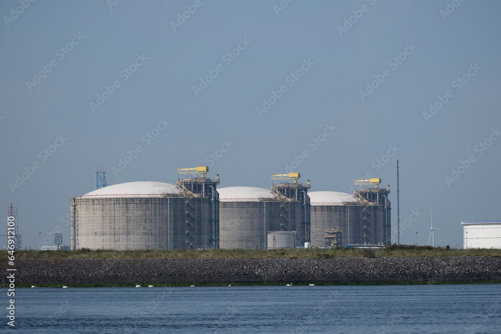 Obraz premium Industrial gas installation. Transshipment and Storage for LNG or liquefied natural gas in the port of Rotterdam. Ships moor for the transport of LNG. Energy price crisis.