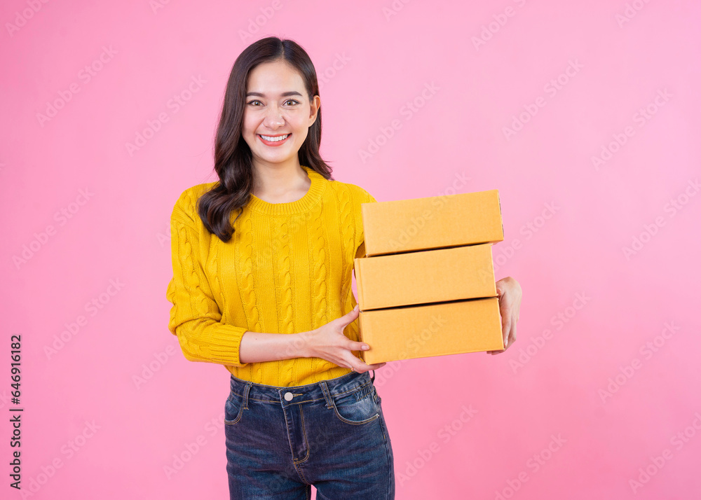 Happy asian woman smiling and holding package parcel box isolated on pink background. Carry delivery goods. Delivery courier and shipping service concept. Happy asian woman smiling and holding package parcel box isolated on pink background. Carry delivery goods. Delivery courier and shipping service concept.