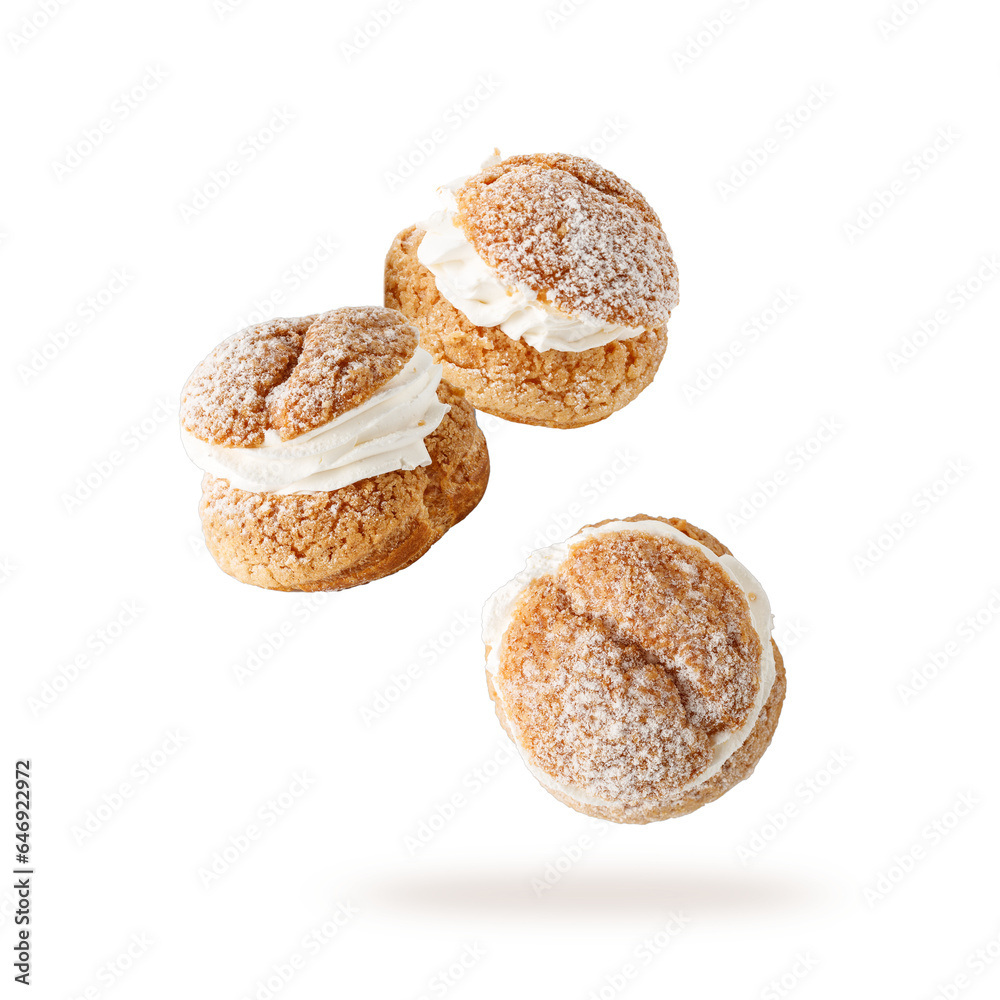 Cream puffs, pastry from choux covered sugar powder closeup falling flying isolated on white background.