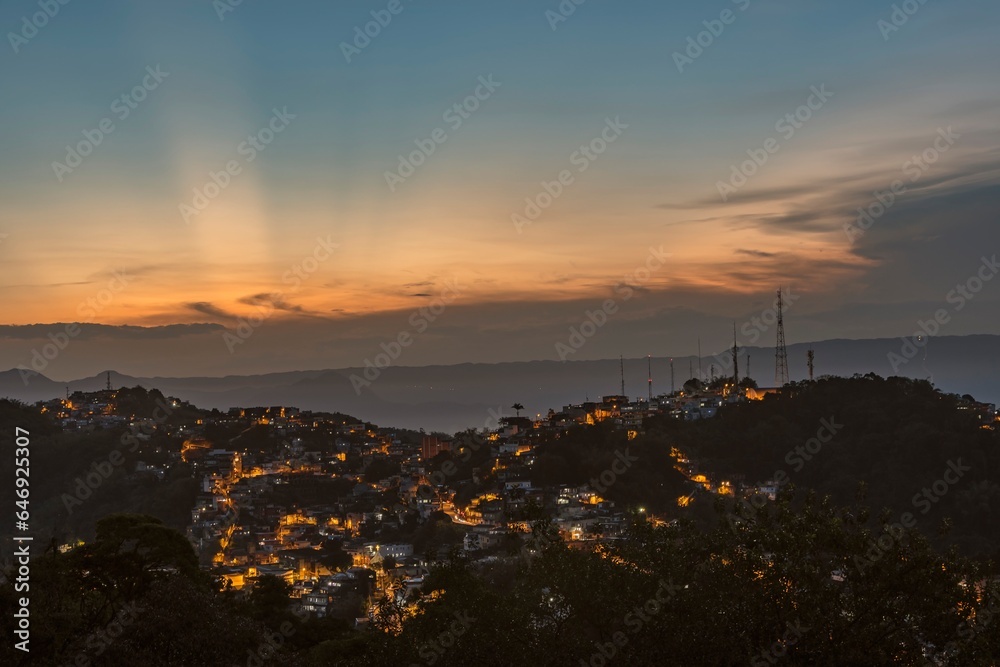 Naklejka premium City of Santos, Brazil. Sunset at Saboó Hill. Neighborhood and illuminated streets. In the background the mountains of the Serra do Mar.
