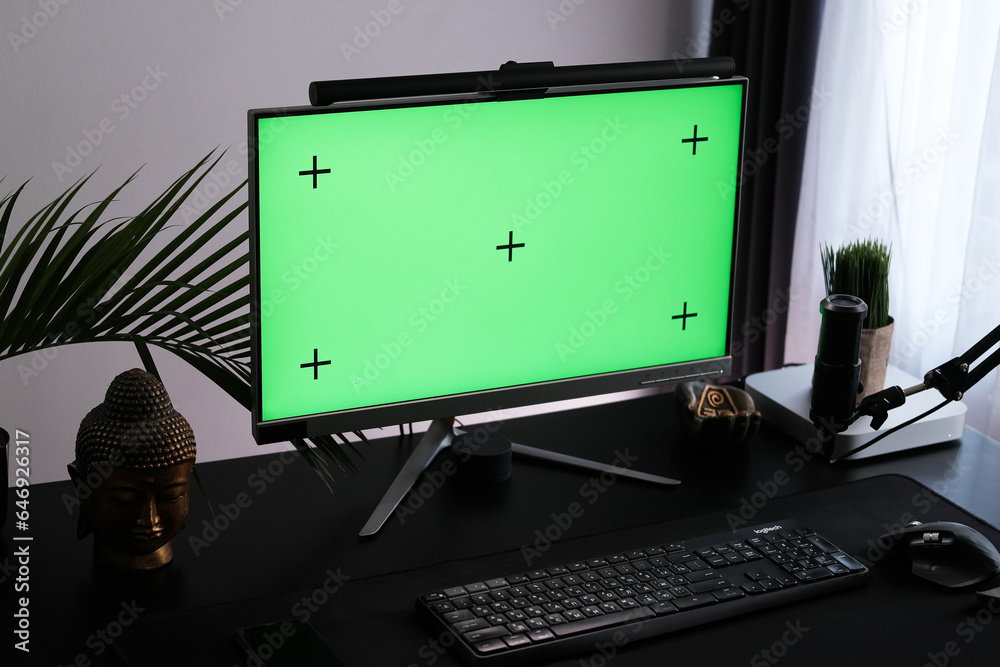 Green monitor screen in a tropical interior. Workspace for podcasting and video blogging. Chroma key for use as a mockup. Green monitor screen in a tropical interior. Workspace for podcasting and video blogging. Chroma key for use as a mockup.