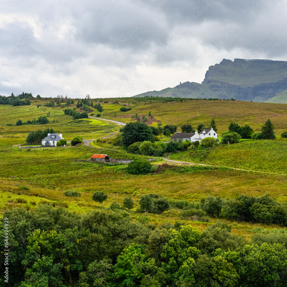 Green landscape with high mountains and cottages on the Isle of Skye, Scotland, UK.