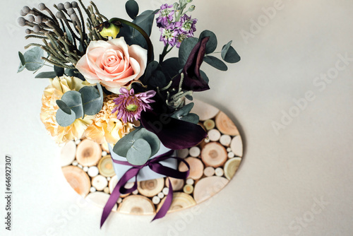 A bouquet of flowers in a rectangular package on a gray concrete background. Bouquet with roses, eucalyptus branches. Background with flowers. Top view