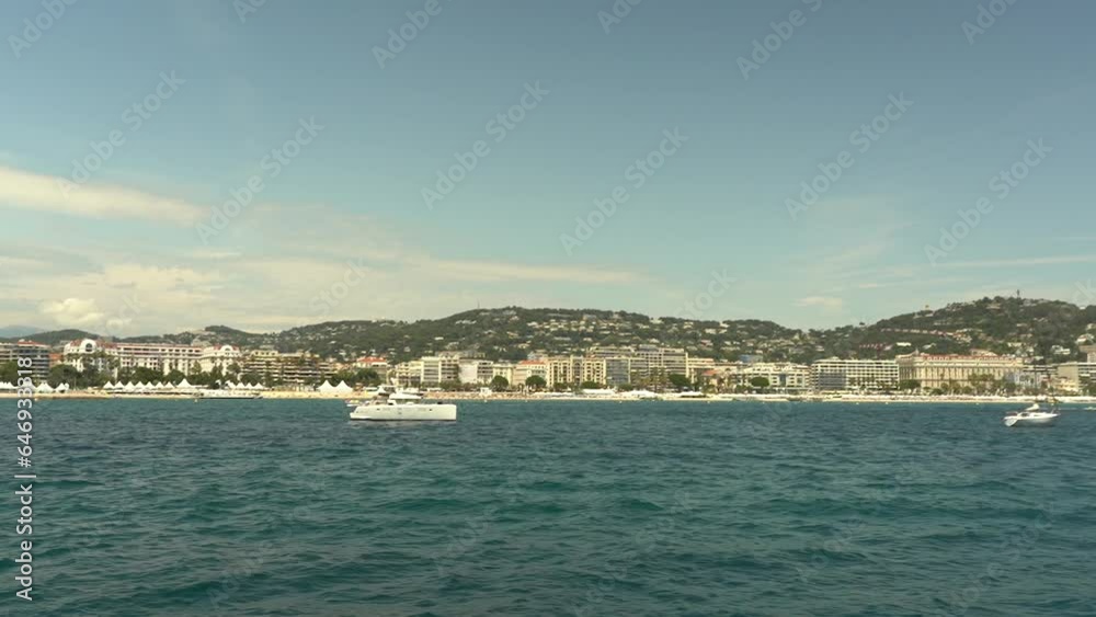A pleasure boat sails from the Lérins Islands towards Cannes, France. View of Cannes from the Mediterranean Sea. A pleasure boat sails from the Lérins Islands towards Cannes, France. View of Cannes from the Mediterranean Sea.