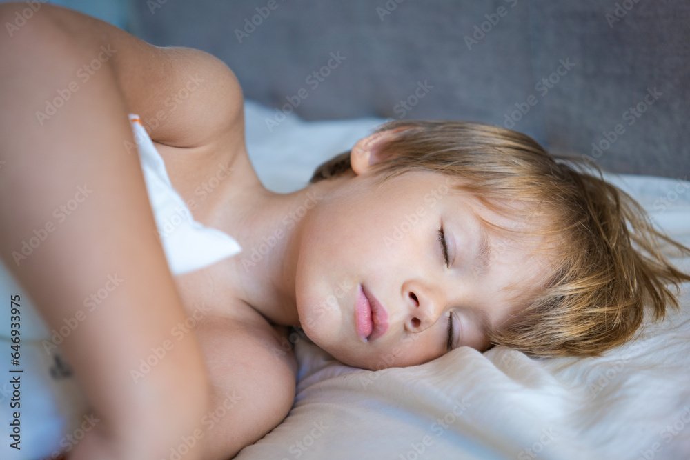 Portrait of a sleeping little boy with golden hair on a white bed Portrait of a sleeping little boy with golden hair on a white bed