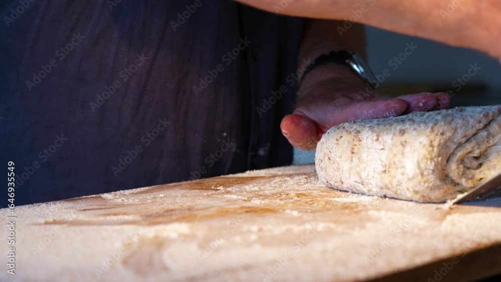 Hands folding and kneading bread dough on a wooden work surface with flour. Close-up. Background for the bakery craft.