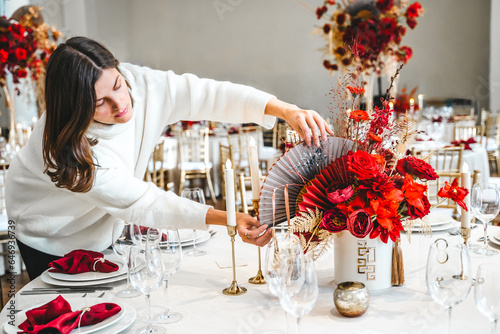 Red gold color flower decor for Chinese New Year celebration. Girl woman florist, decorator, organizer of events, parties, wedding planner making floral arrangement, festive bouquet, table decoration