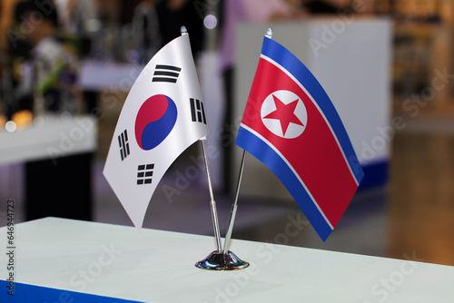 Two small table flags of South Korea and North Korea together at some event or fair, as a symbol of cooperation between the two states. Joint business between North Korea and South Korea