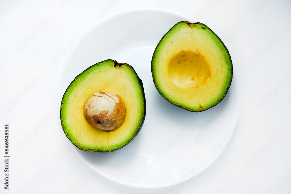 Sliced green avocado on a white background. Pieces of green vegetable on a white plate. Delicious food for a vegan.