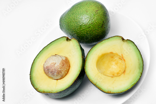 Sliced green avocado on a white background. Pieces of green vegetable on a white plate. Delicious food for a vegan.